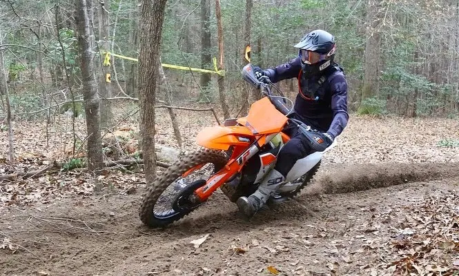Sam cornering his orange KTM on a dirt trail