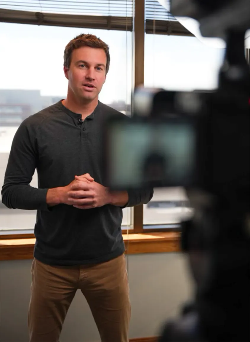 Sam Silvey talking to a video camera on set at the office