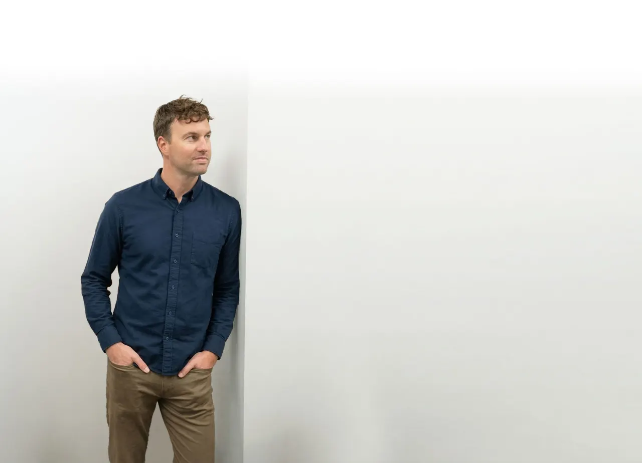 Sam Silvey leaning against a white wall at the Spectruss office